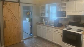 Una cocina con armarios blancos, estufa y microondas.