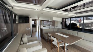 Un intérieur moderne comprenant un coin repas, une cuisine et un espace détente près d’une grande fenêtre.