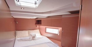 A compact, well-lit cabin with a bed, a small window, and built-in storage.