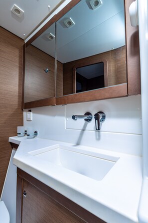 Une salle de bain avec un lavabo blanc, des meubles en bois, un miroir et des toilettes.
