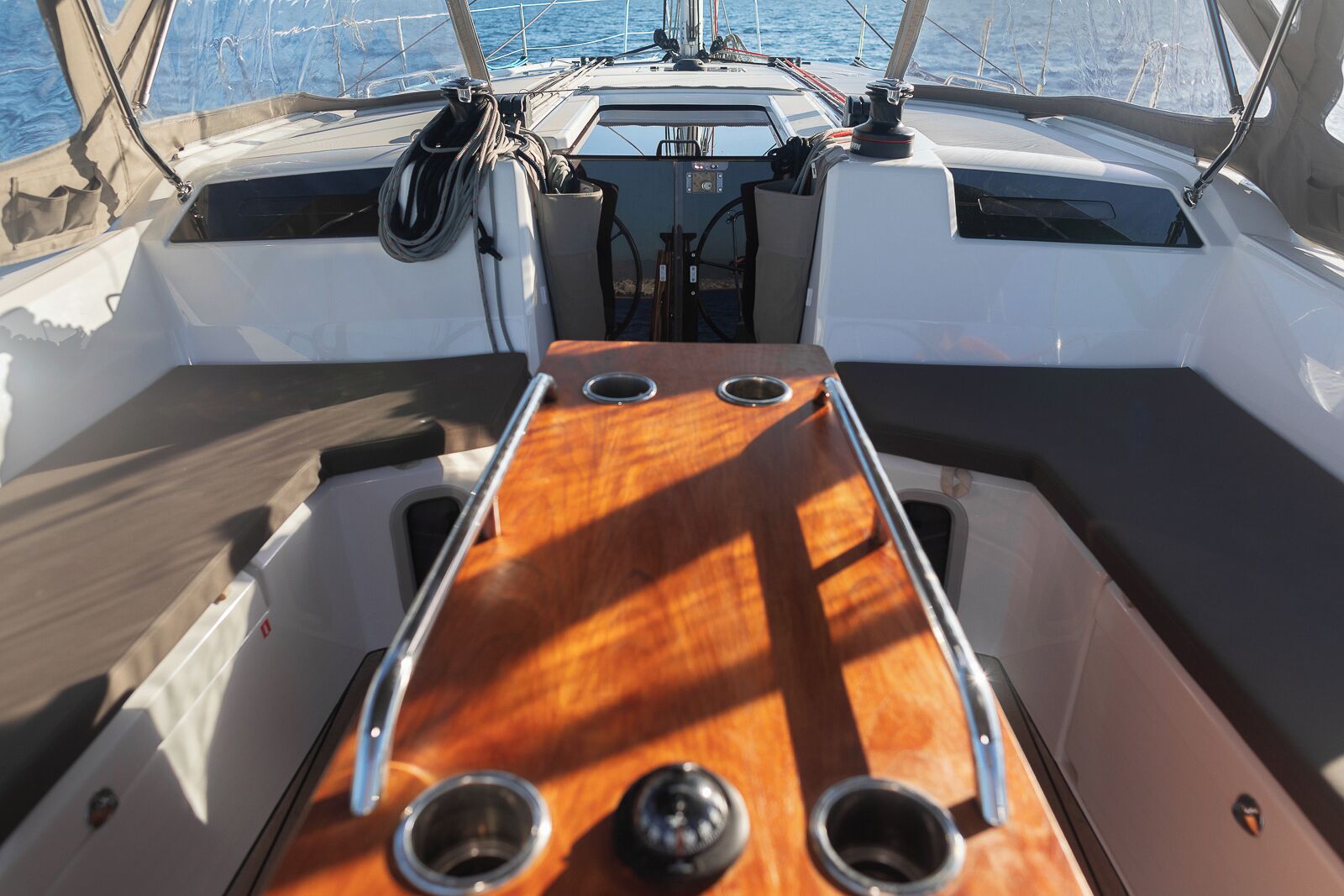 Cubierta de barco con una consola central, dos ventanas laterales y un timón.