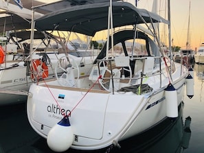Ein weißes Boot mit der Aufschrift 'althea' und 'r.n. Piraeus' am Bug, liegt in einer Marina mit anderen Booten festgemacht.