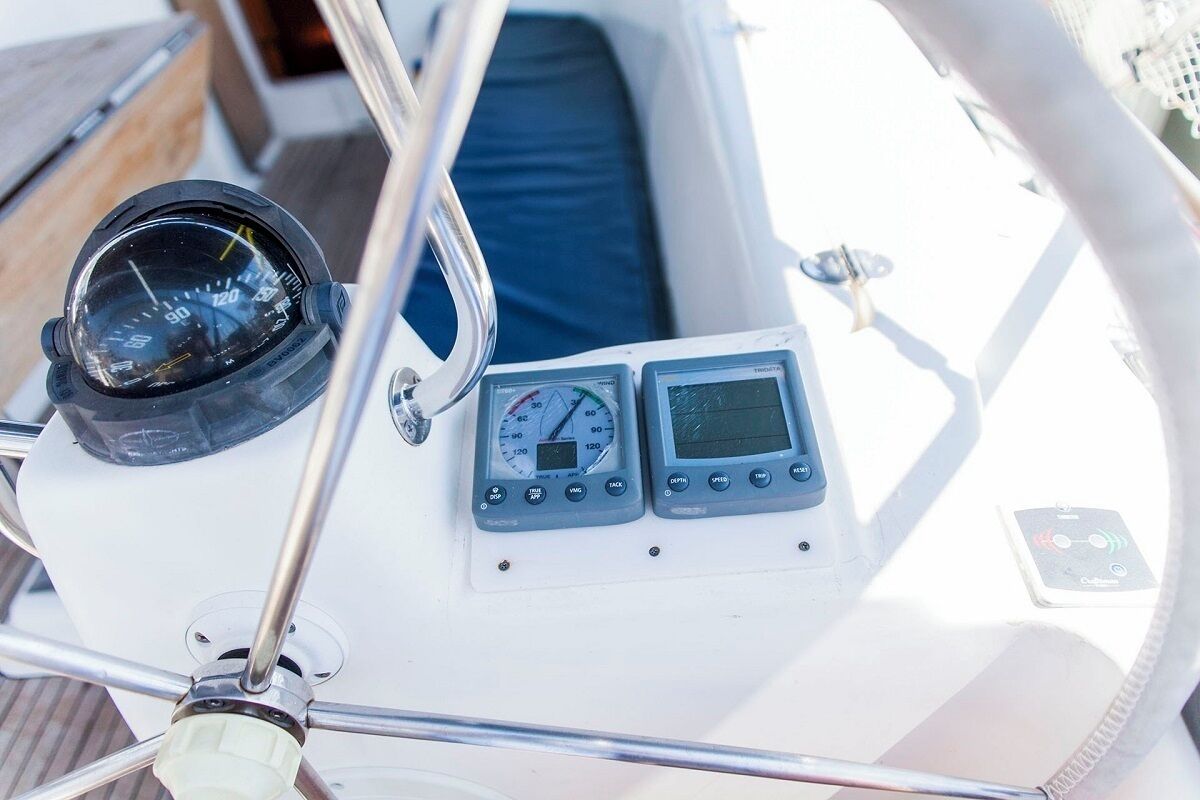 Un panneau de commande de bateau comprenant une boussole, un compteur de vitesse et deux écrans numériques.