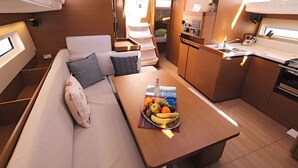 A compact galley with a dining table, a sofa with cushions, and a small kitchenette.