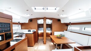 A compact, modern kitchen with wooden cabinetry, a central island, and a dining area with white upholstered seating.