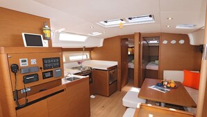 A compact galley with a stove, a sink, and a small refrigerator. There is a dining area with a table and chairs, and a small seating area with a bench.