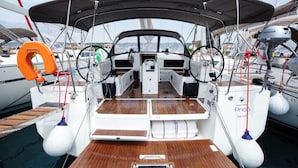 A boat's deck with a steering wheel, life preserver, and a water pump.