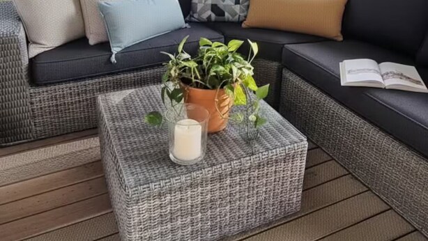 A covered outdoor seating area with a sofa, cushions, a small table with a plant, and a book. - 5* 2025 - Siblu La Réserve sleeps 8, 2 bathrooms (Gastes)