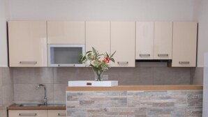 Een keuken met beige kastjes, een arduinen spatwand, een roestvrijstalen spoelbak en een magnetron boven de kastjes.