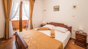 Une chambre d’hôtel avec un lit, une table de chevet, une chaise et une fenêtre avec des rideaux.