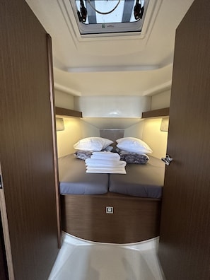 A compact, well-lit interior with a bed, pillows, and a skylight.