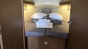 Interior compacto e bem iluminado, com cama, almofadas e um claraboia.