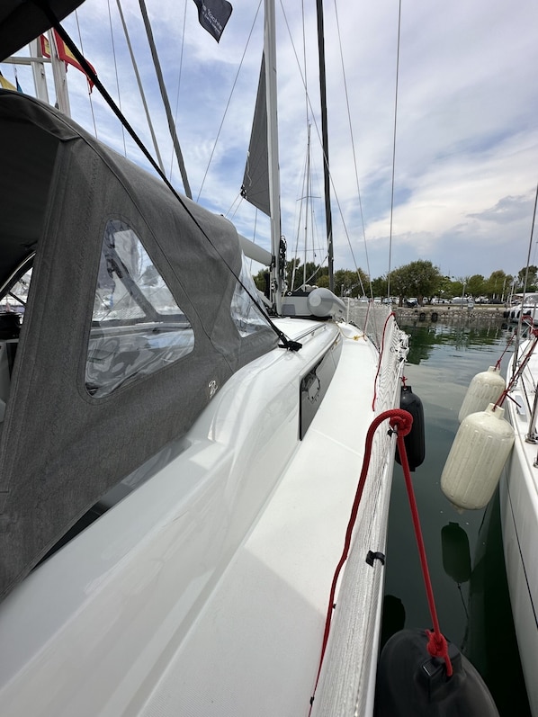 A sailboat docked at a marina with a clear view of the water and other boats in the background.