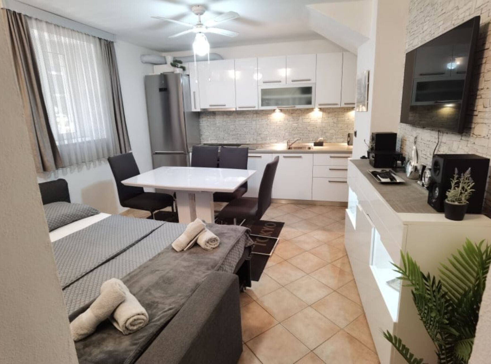 Quarto de hotel compacto com cozinha compacta, área de refeições e cama com toalhas.