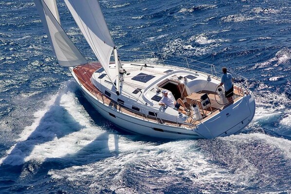 A sailboat with a cabin, deck seating, and a person steering.