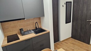 Et kompakt køkken med vask, lille bordplade og spiseplads med bord og stole.