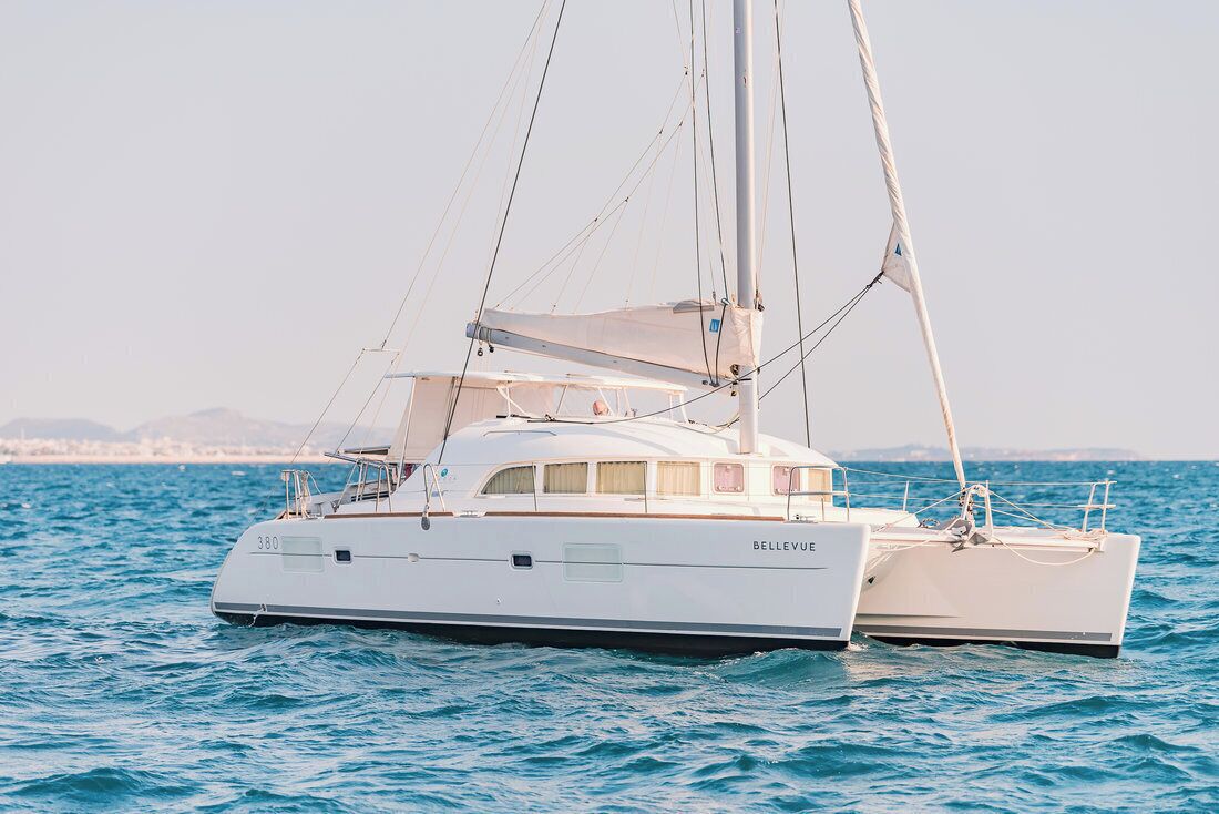 Un velero blanco llamado 'BELLEVUE' navegando sobre aguas tranquilas bajo un cielo despejado.
