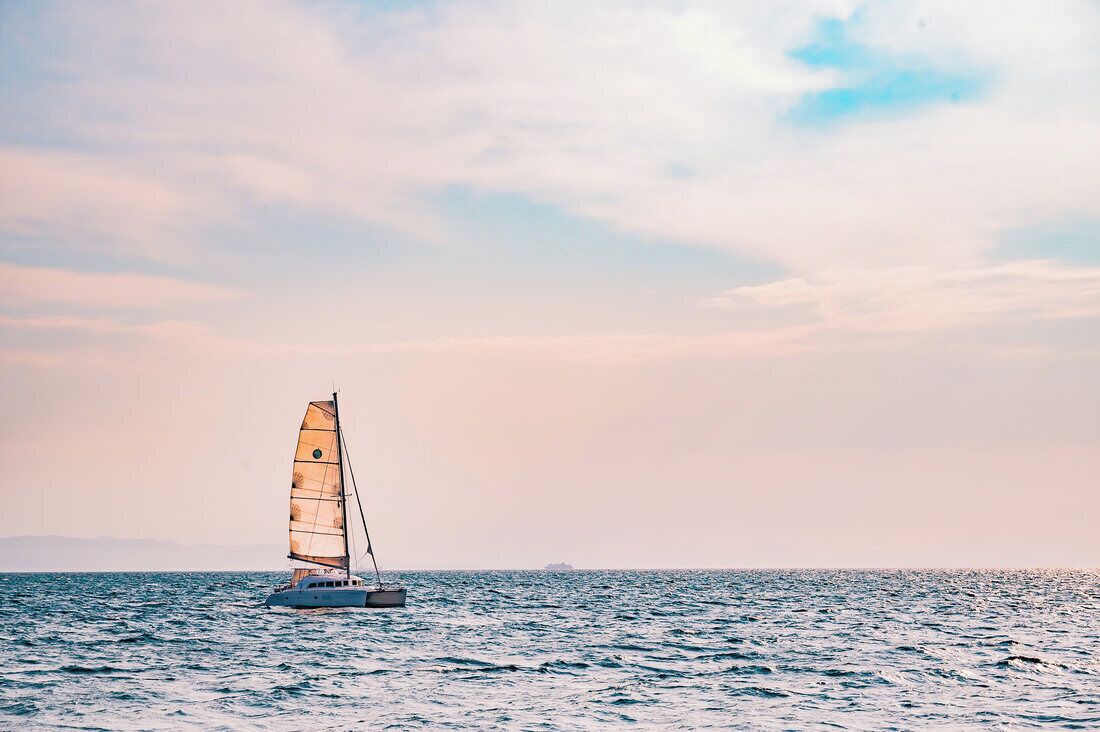 A sailboat on calm waters with a clear sky.