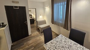 Une chambre d’hôtel de taille réduite, comprenant un lit, une petite table, deux chaises, un bureau avec un ordinateur, une fenêtre avec des rideaux et une porte.