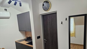Une cuisine de taille modeste, dotée d’une porte en bois foncé, d’une horloge murale et d’un grand miroir.