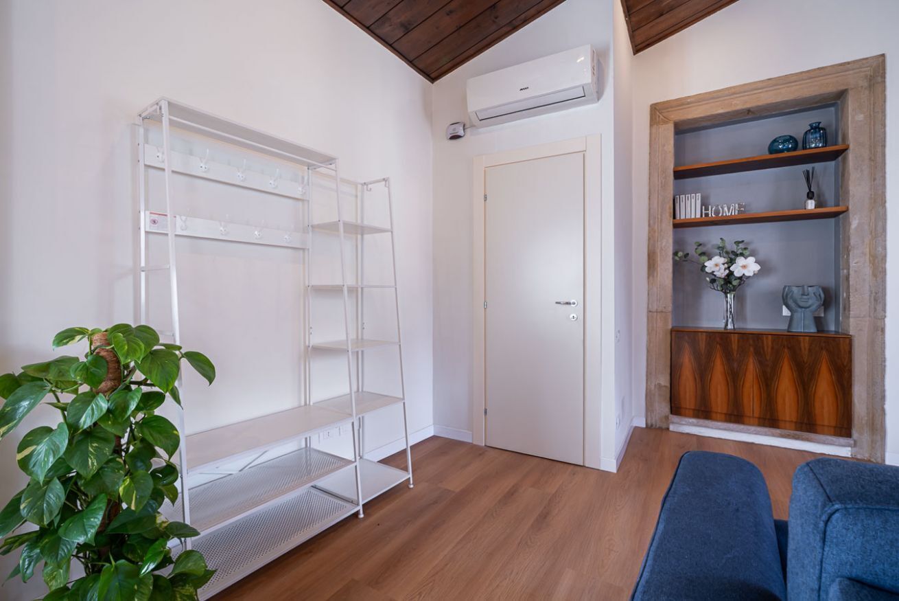 A room with a white shelving unit, a closed door, a blue sofa, and a potted plant.