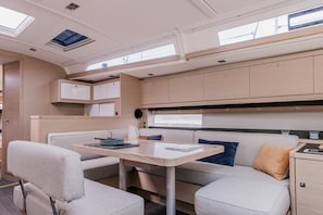 A compact RV interior with a dining area, kitchenette, and a small sleeping space.