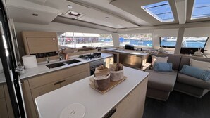 A yacht interior with a kitchen, dining area, and seating. - Sun-Kissed Sailing Adventure in the Ionian Islands (Nidri)