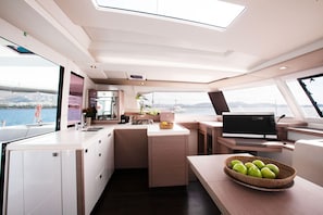 A modern kitchen with a large island, a flat-screen TV, and a view of the water. - Sun-Kissed Sailing Adventure in the Stunning Islas Cícladas (Paros)