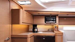 Una cocina compacta con microondas, cafetera y un refrigerador pequeño.