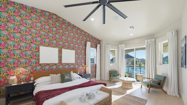 Un dormitorio con una cama grande, un ventilador de techo, vistas al exterior y una ventana con cortinas.