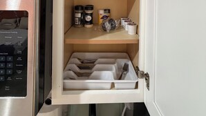 A kitchen with a microwave, a cabinet with shelves containing jars, a kettle, and a kettle lid.