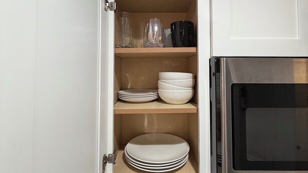 A kitchen with a built-in cabinet containing plates, bowls, and glasses.