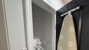 A bathroom with a shower, a towel rack, and an ironing board.