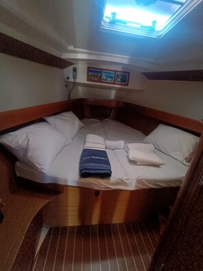 A compact bed with a headboard, a small window, and a wall-mounted phone. - Sun-kissed Sailing Adventure in the Ionian Islands (Preveza)
