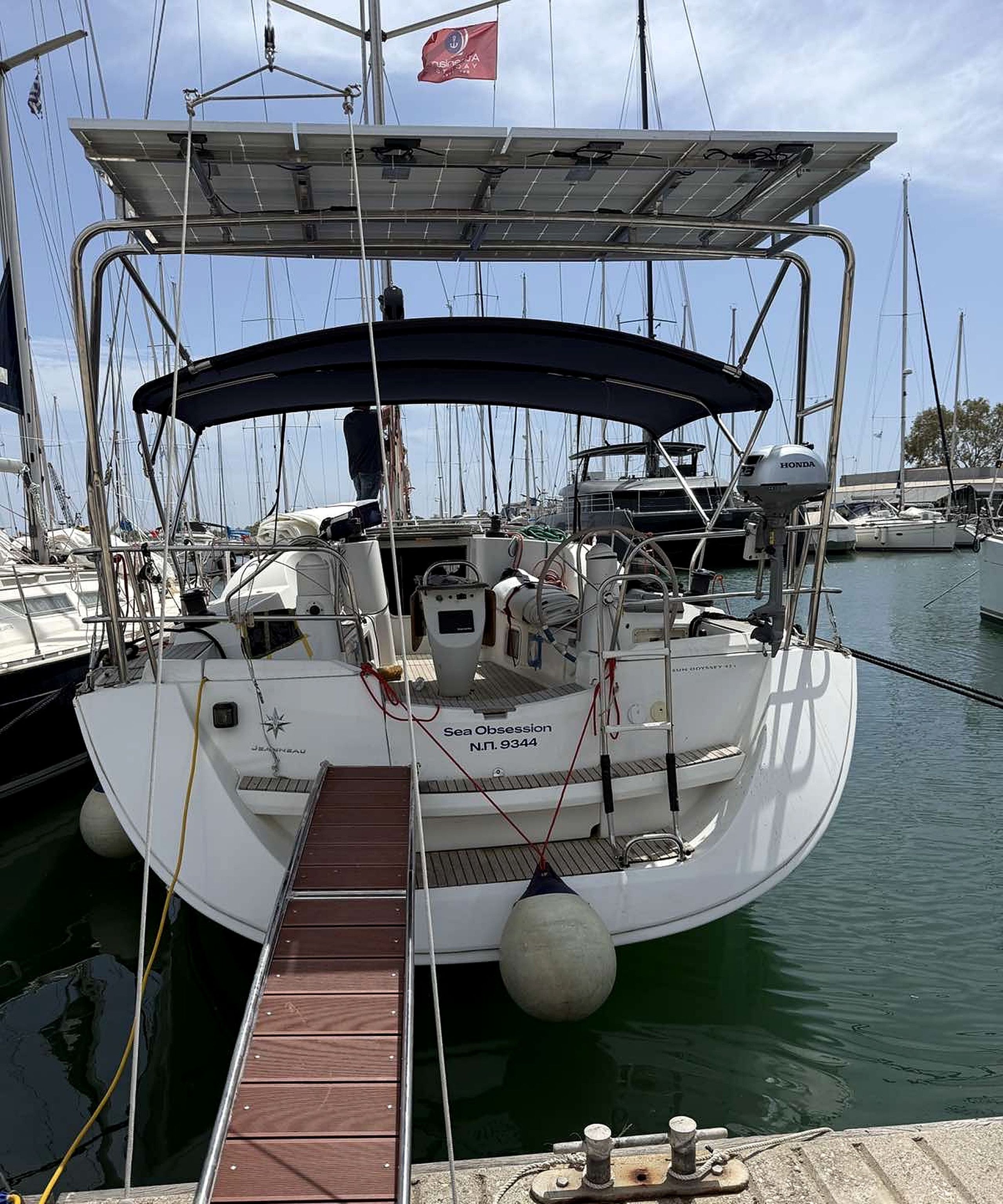 A sailboat docked at a marina with a covered deck, a steering wheel, and a winch.