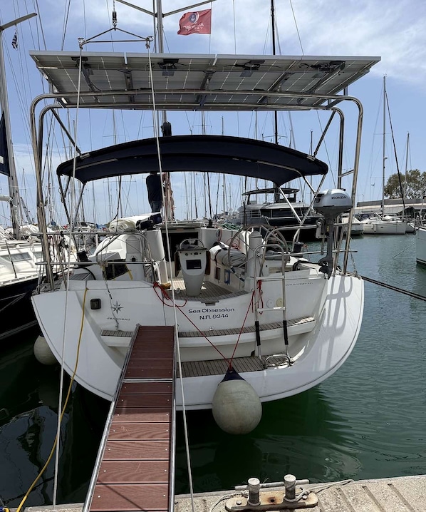 A sailboat docked at a marina with a covered deck, a steering wheel, and a winch.