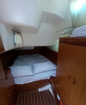 A compact cabin with a bunk bed, a small wooden cabinet, and a window with curtains.