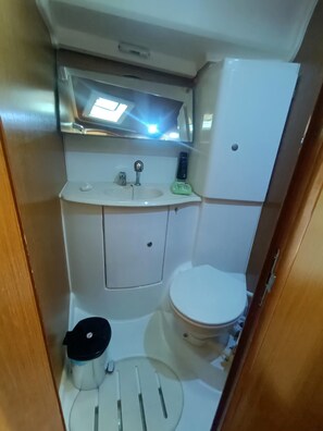Un bany petit i funcional amb un lavabo, vàter i un petit cendrer.