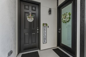 A black door with a welcome sign, a wreath on the glass door, and a small plant on the wall. - Serene 1-bedroom studio minutes away from Medical center and Downtown Houston (Houston)