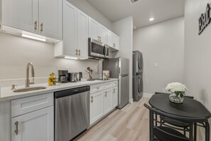 A modern kitchen with white cabinetry, stainless steel appliances, and a black dining table with a vase of flowers. - Serene 1-bedroom studio minutes away from Medical center and Downtown Houston (Houston)