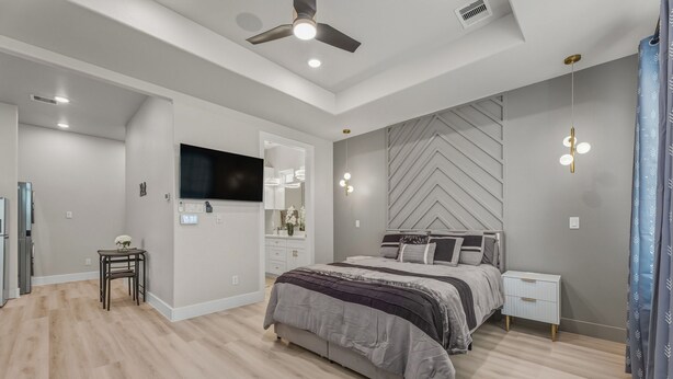 Une chambre à coucher avec un lit, une télévision, un ventilateur de plafond et une table de chevet.