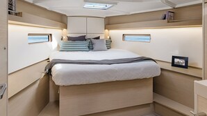 A compact, well-lit bedroom with a bed, bedside tables, and a skylight.