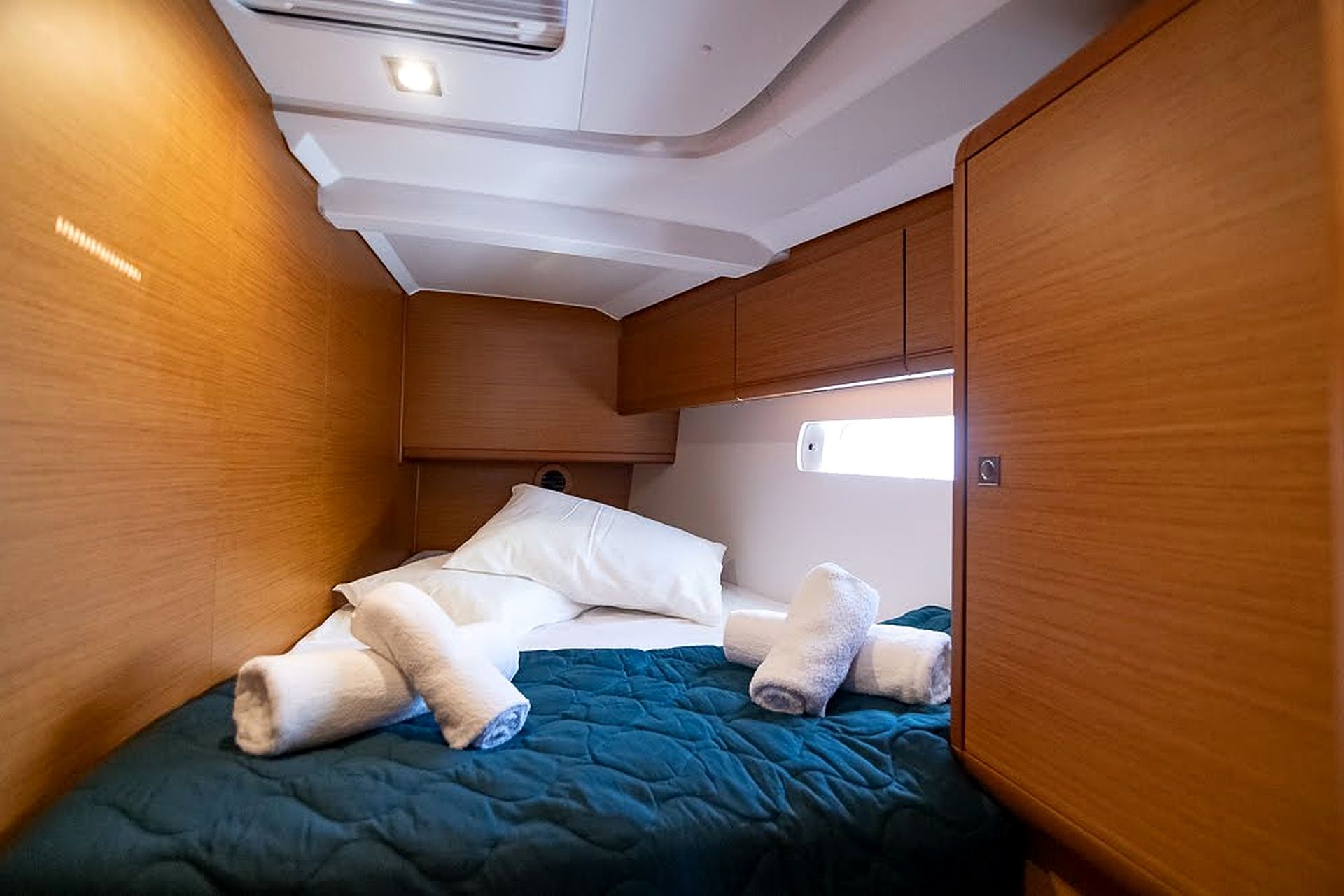 A compact, well-lit interior space with a bed, pillows, and a blanket.