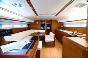 A compact interior with a central table, seating, and a kitchenette area. - Sun-Kissed Sailing Adventure in the Stunning Islas Cícladas (Paros)