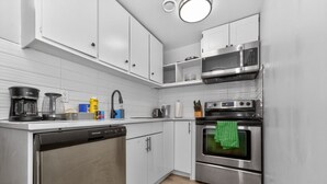 Een moderne keuken met roestvrijstalen apparatuur, witte kasten en een vaatwasser.