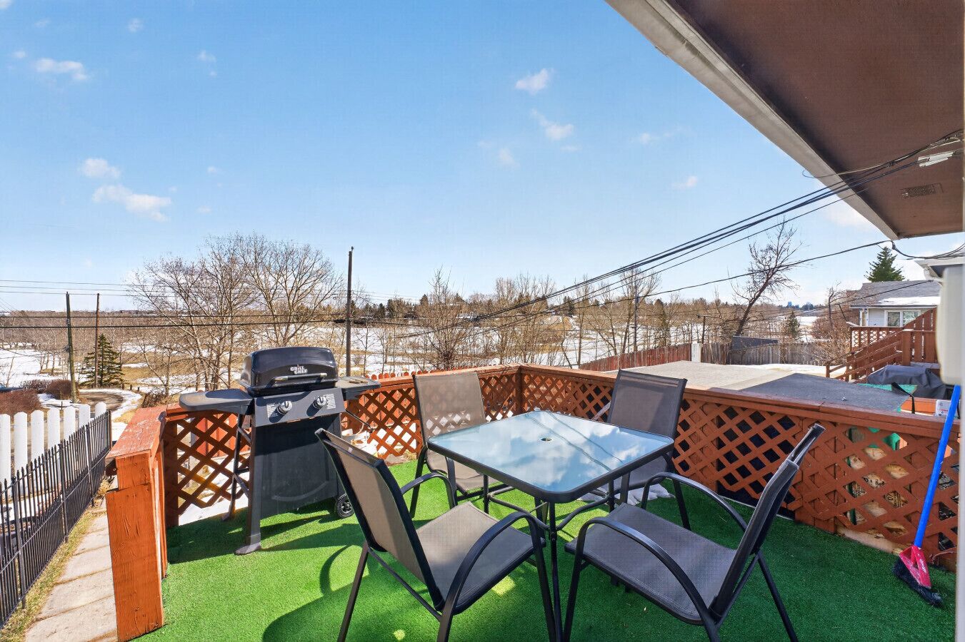 Eine Terrasse im Freien mit Grill, Stühlen und Tisch.