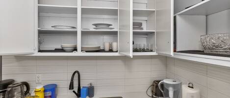 A kitchen with white cabinets, a stainless steel sink, and a microwave.