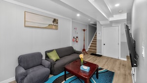 Een moderne woonkamer met een bank, fauteuil, salontafel en kunst aan de muur.