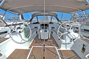 Das Deck eines Bootes mit Steuerrädern, einer Mittelkonsole und einem Holzboden.