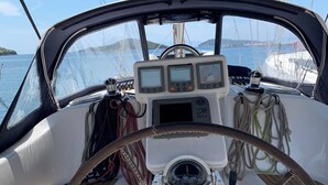 Cockpit på en båd med rat, kontrolpaneler og reb.